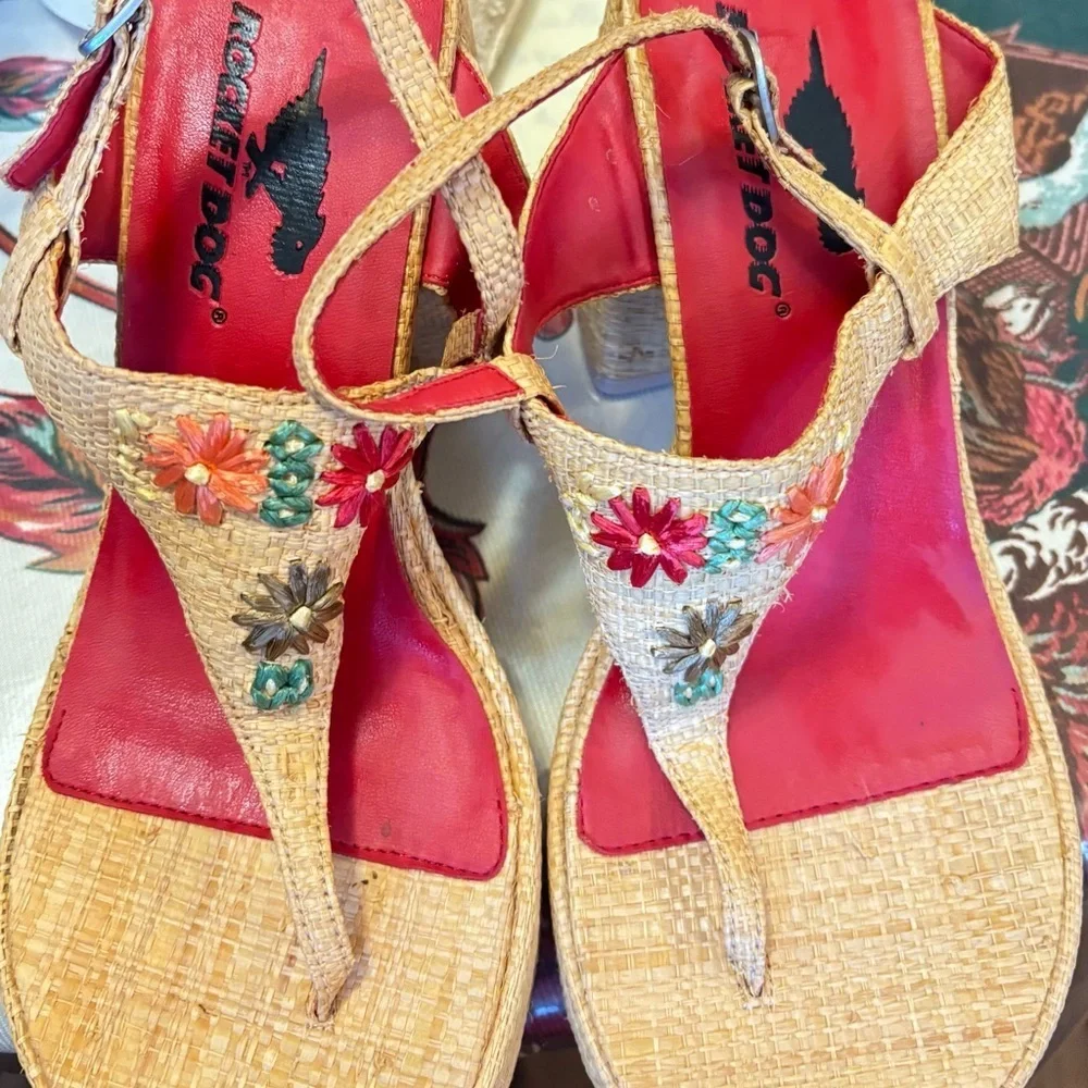 Rocket Dog brand wedges sandals with raffia uppers and floral embellishments.